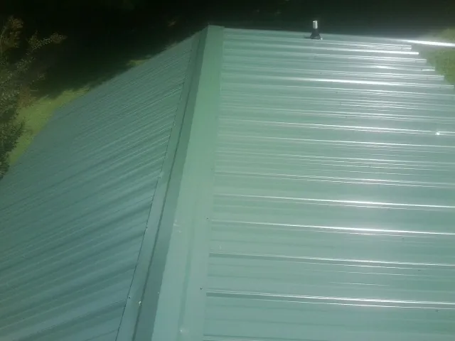 New green metal panels meeting at the ridge of a roof — Flat Roof Repair work by our crew in Burlingame