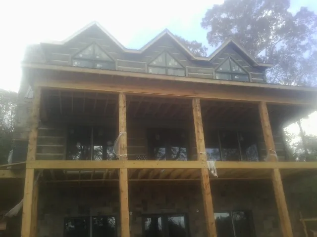 Dormers and porch framing on a large log home under construction — Roof Coating work by our crew in Burlingame