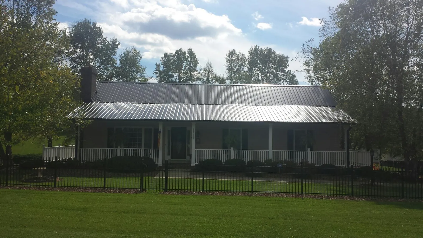 Gray metal roof on a brick ranch with a full width front porch — Gutter Guard Installation work by our crew in Burlingame
