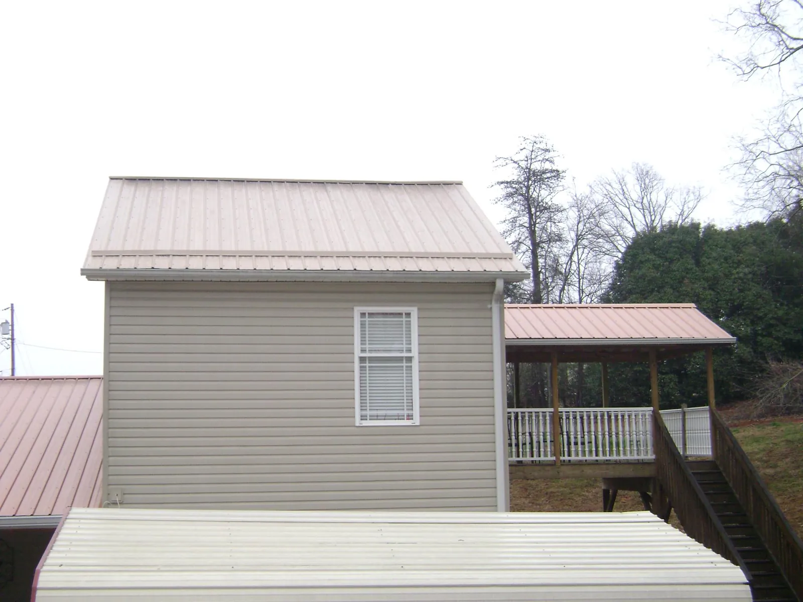 Tan metal roofs on a two story addition and attached porch, from a Roof Replacement job in Burlingame
