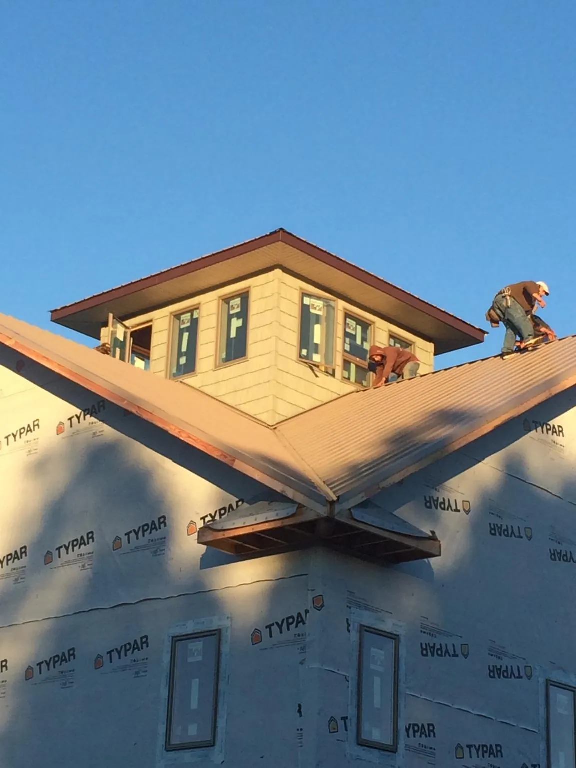 Roofers working around a rooftop cupola on a new metal roof at sunset — Roof Waterproofing in Burlingame by Roofing Brothers